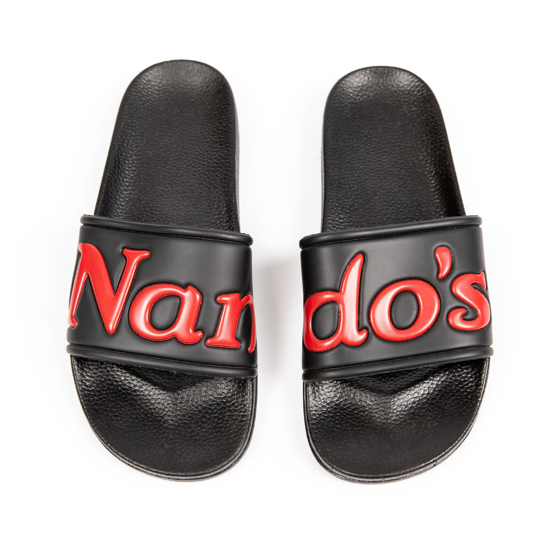 Black sliders featuring the Nando’s logo across the straps.