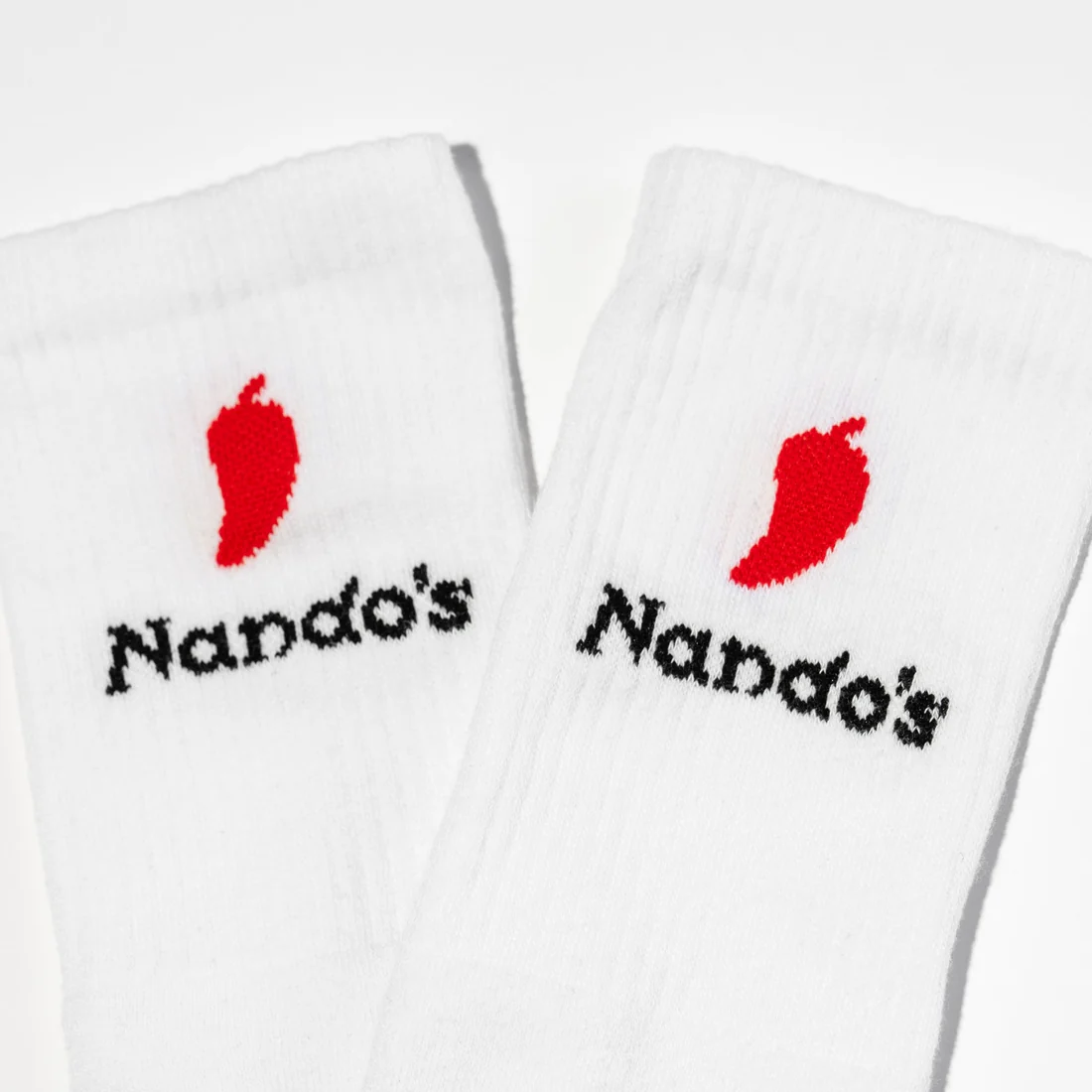 White socks embroidered with mini chillies and the Nando’s logo.